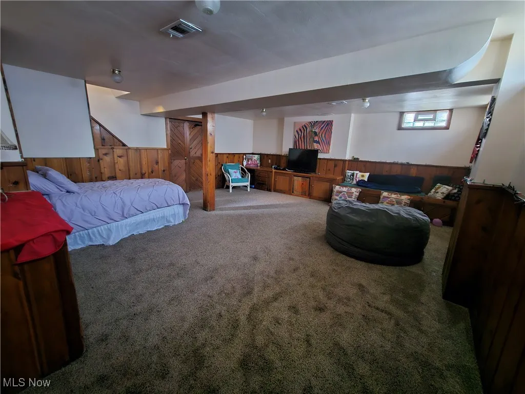 Carpeted bedroom with wood walls and a wainscoted wall