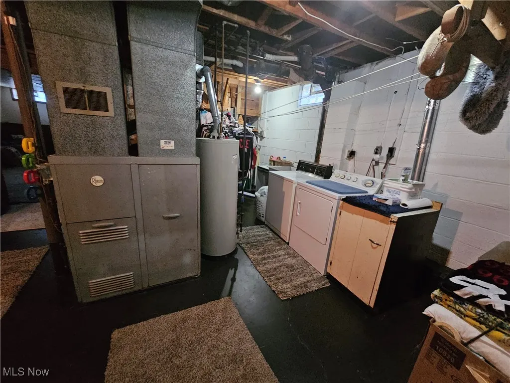 Washroom featuring heating unit, water heater, and washing machine and clothes dryer