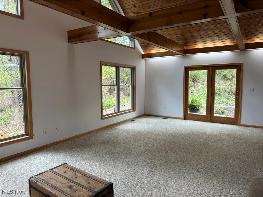 Carpeted spare room featuring baseboards and wood ceiling