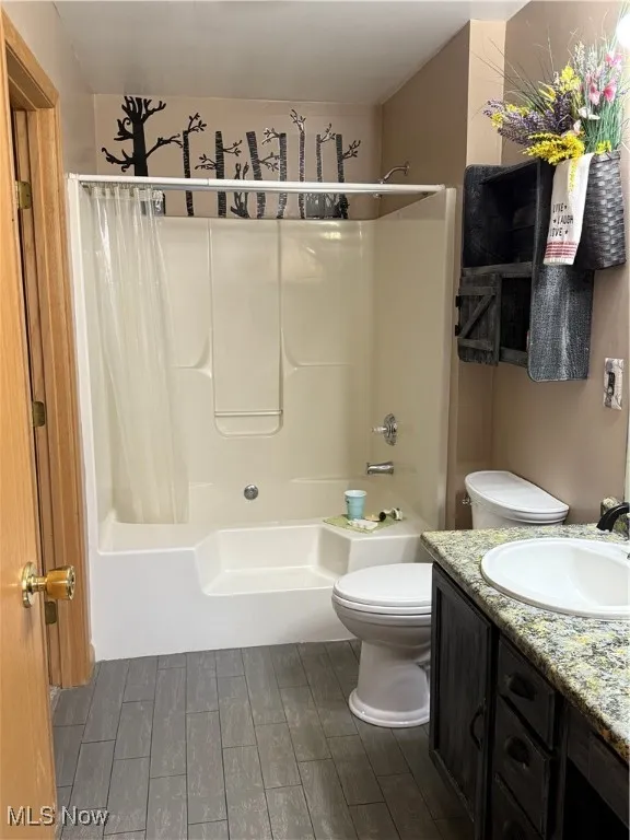 Bathroom with shower / bath combo with shower curtain, vanity, and wood tiled floors
