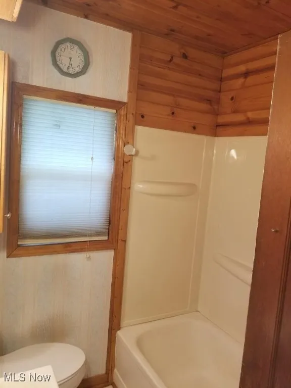 Bathroom featuring washtub / shower combination, wood ceiling, wood walls, and wallpapered walls