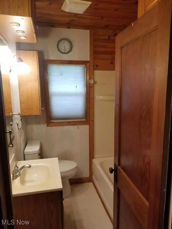 Full bathroom with vanity, bathing tub / shower combination, wood ceiling, and wood walls