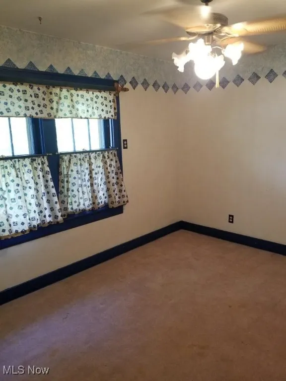 Spare room featuring carpet floors and baseboards
