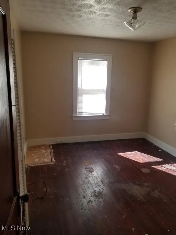 Unfurnished bedroom featuring dark wood-type flooring and a textured ceiling