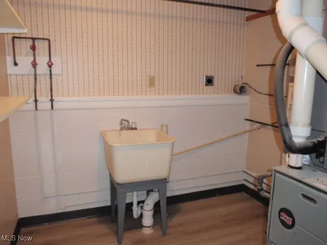 Utility room featuring heating unit and a sink