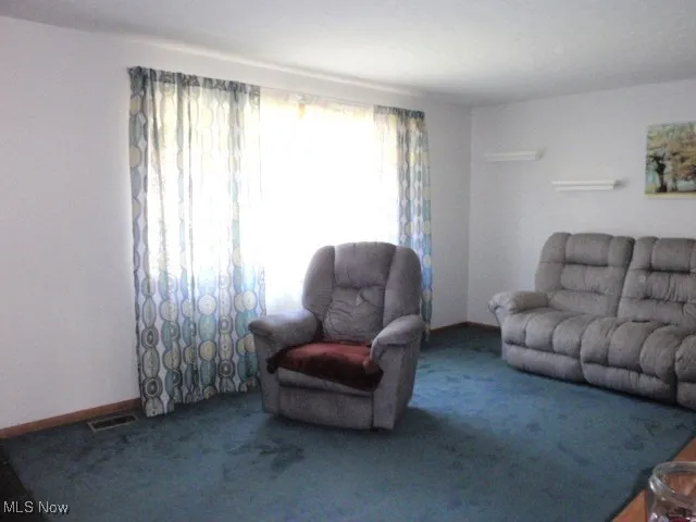 Carpeted living area featuring baseboards