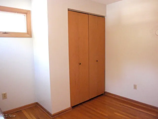 Unfurnished bedroom with wood finished floors and a closet