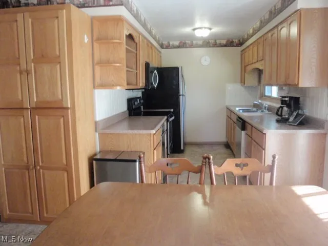 Kitchen with light countertops, stainless steel appliances, open shelves, and light brown cabinets and pantry
