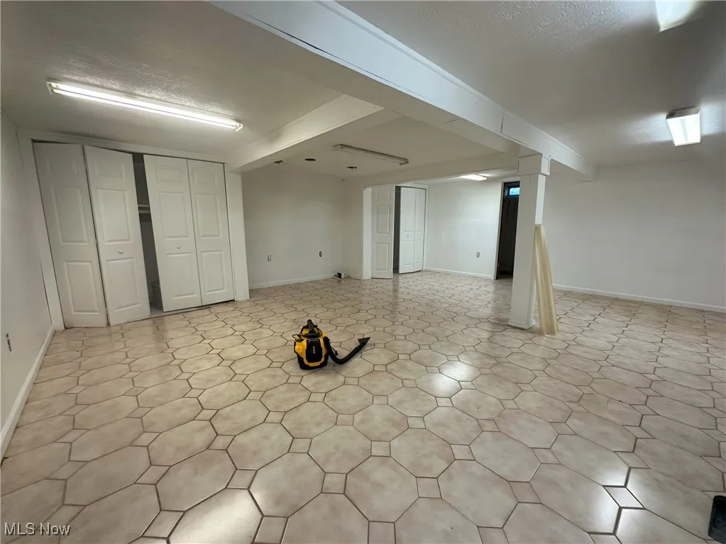 Finished basement with a textured ceiling and light floors