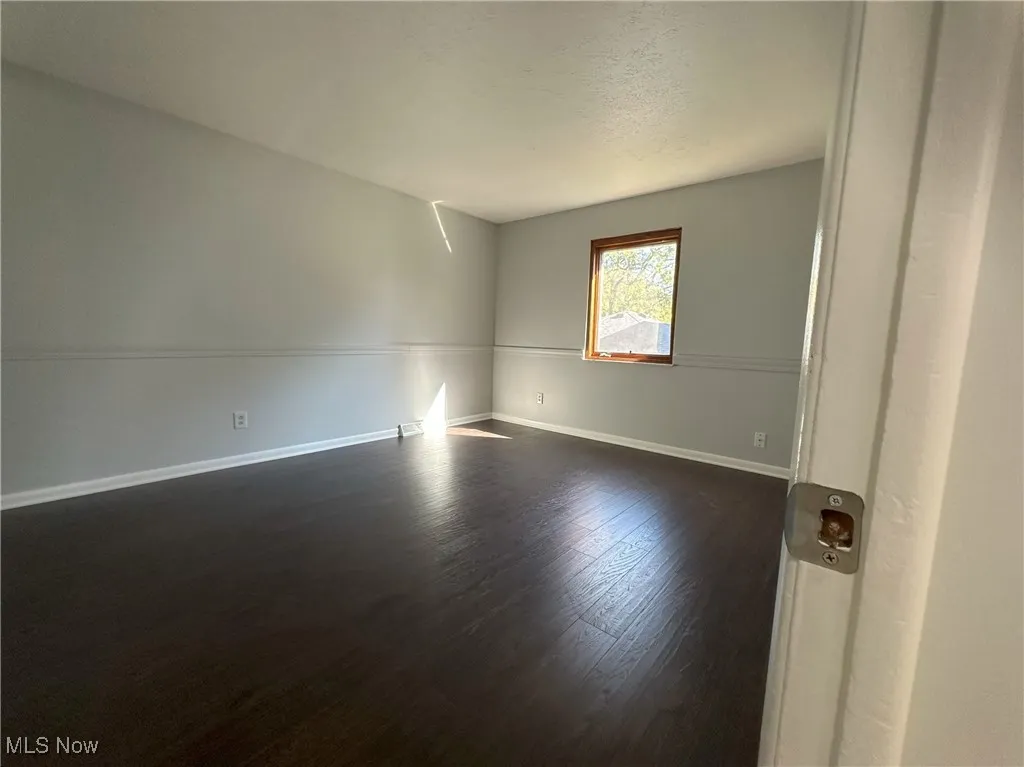 Empty room featuring dark wood-style flooring and a textured ceiling