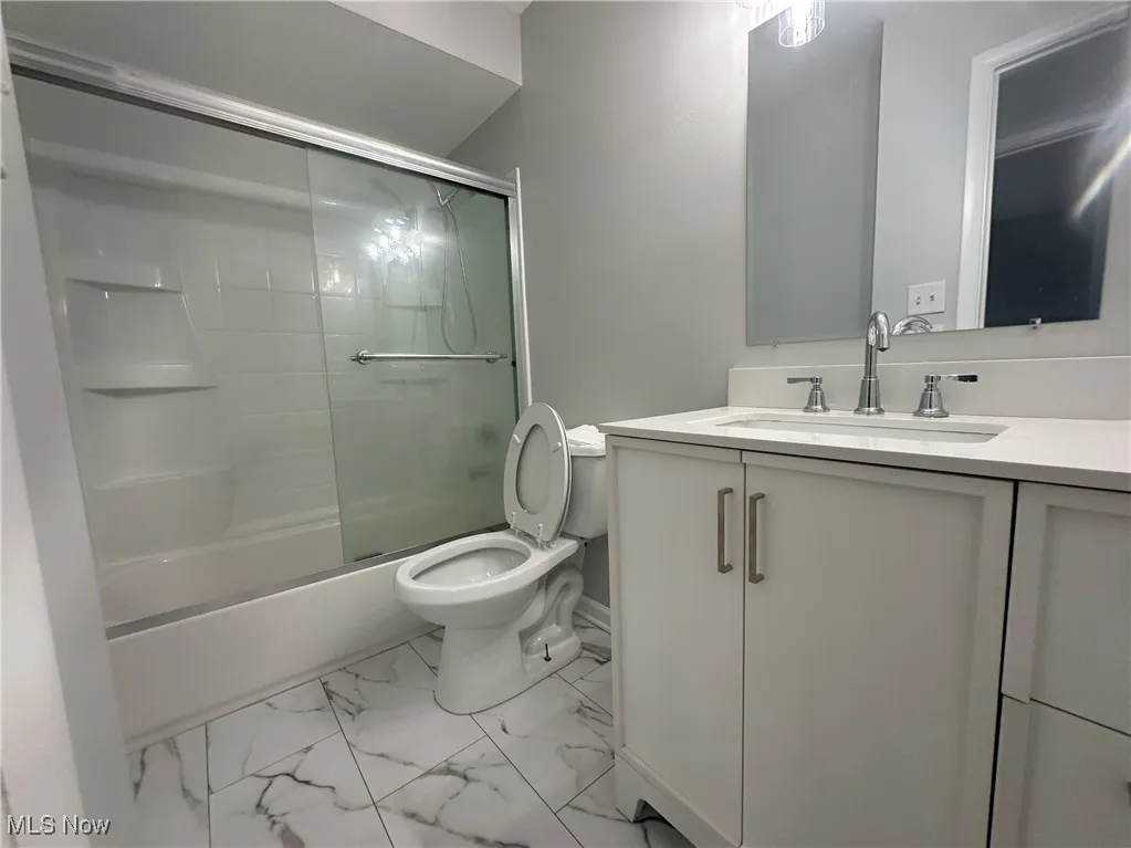 Full bathroom with vanity, shower / bath combination with glass door, and light marble finish flooring