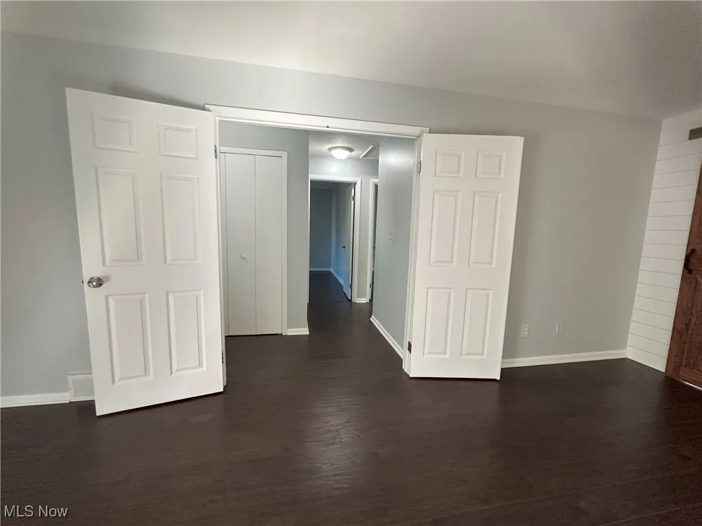 Empty room featuring dark wood-style floors and baseboards