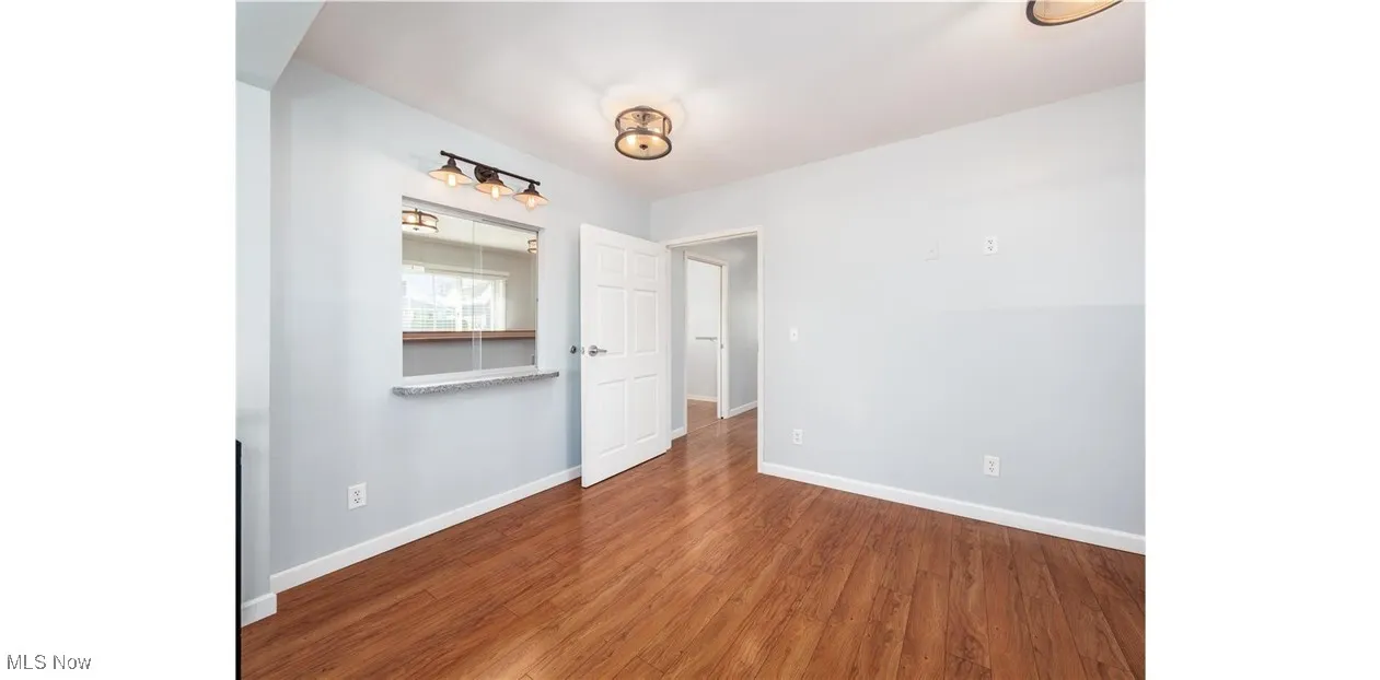 Empty room featuring dark wood-type flooring and baseboards