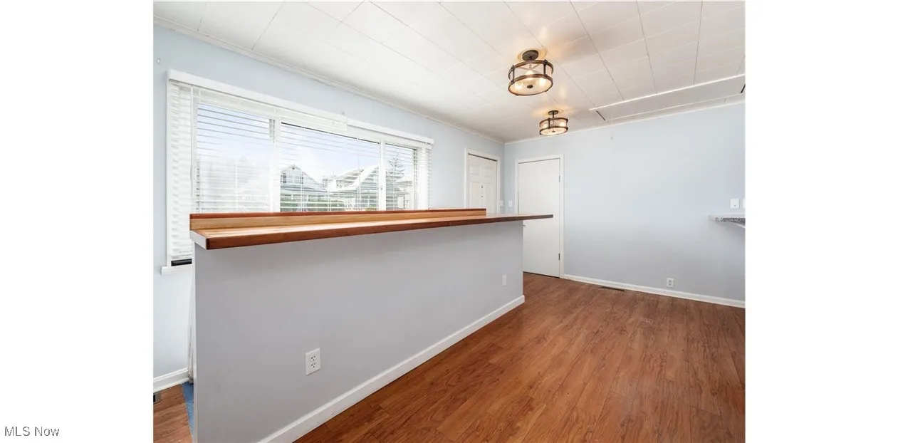 Hallway with dark wood-type flooring, attic access, and ornamental molding