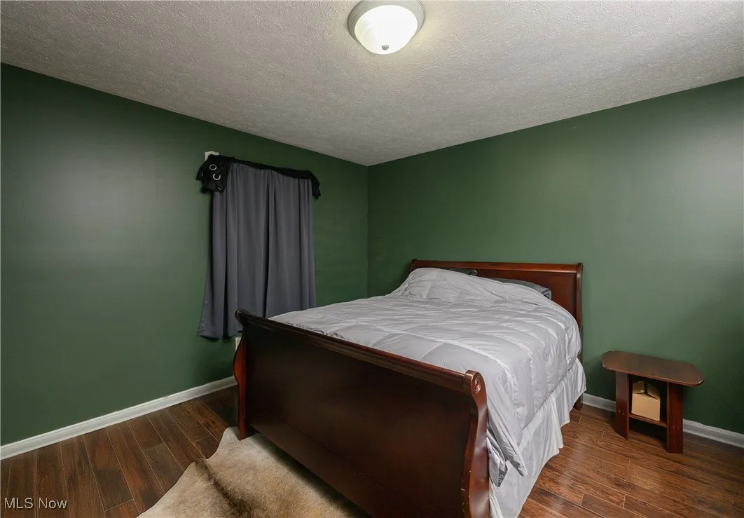 Bedroom featuring a textured ceiling and dark wood-style flooring