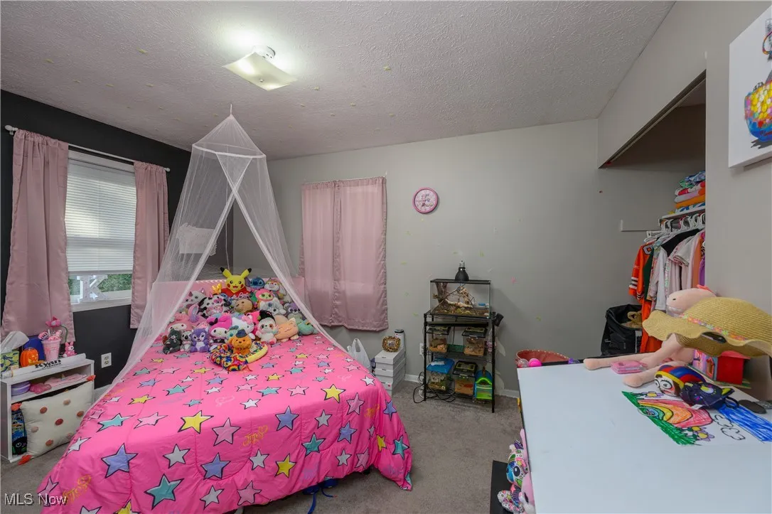 Bedroom featuring a textured ceiling, light colored carpet, and a closet