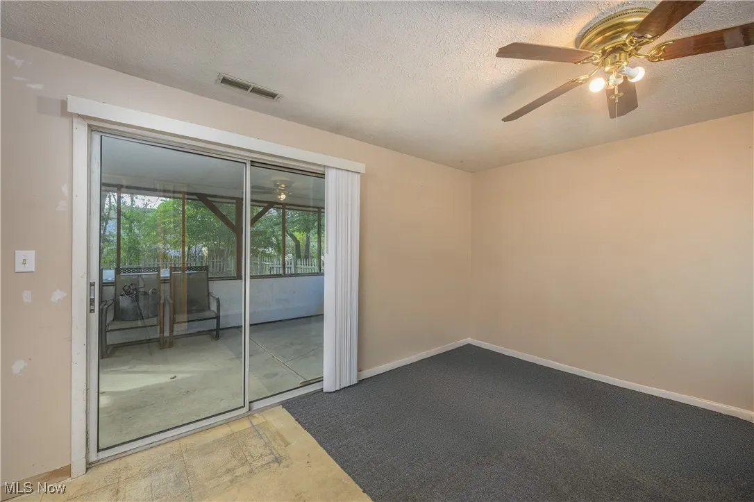 Empty room featuring ceiling fan, a textured ceiling, and carpet flooring