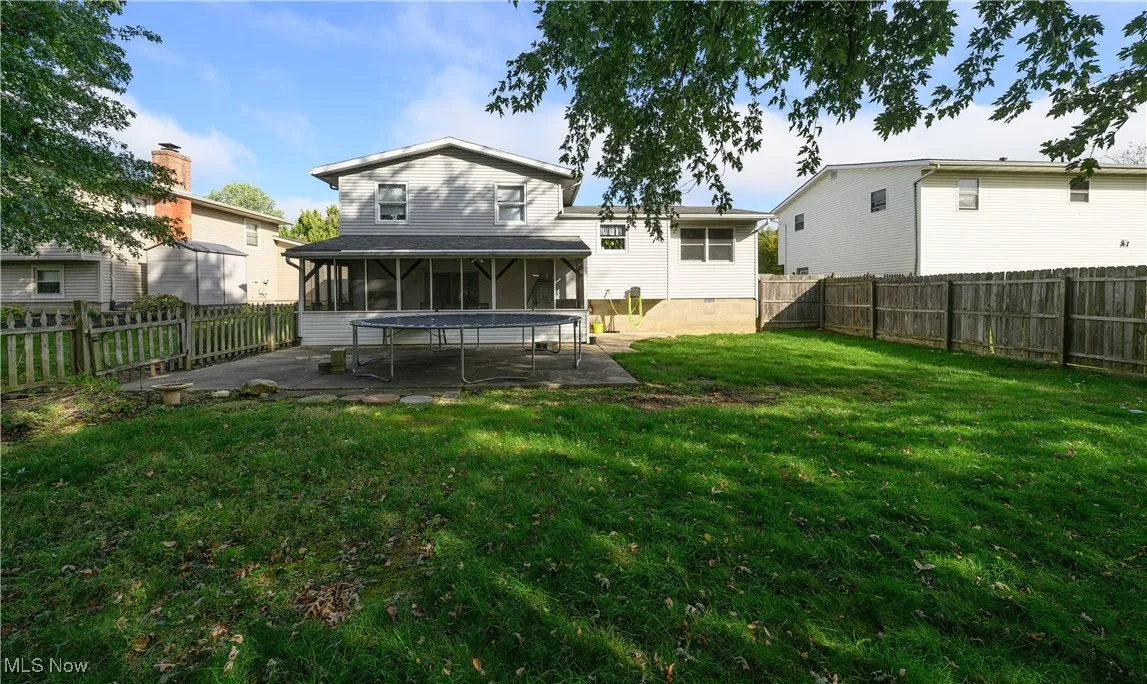 Rear view of property with a sunroom, a fenced backyard, a patio, and a trampoline