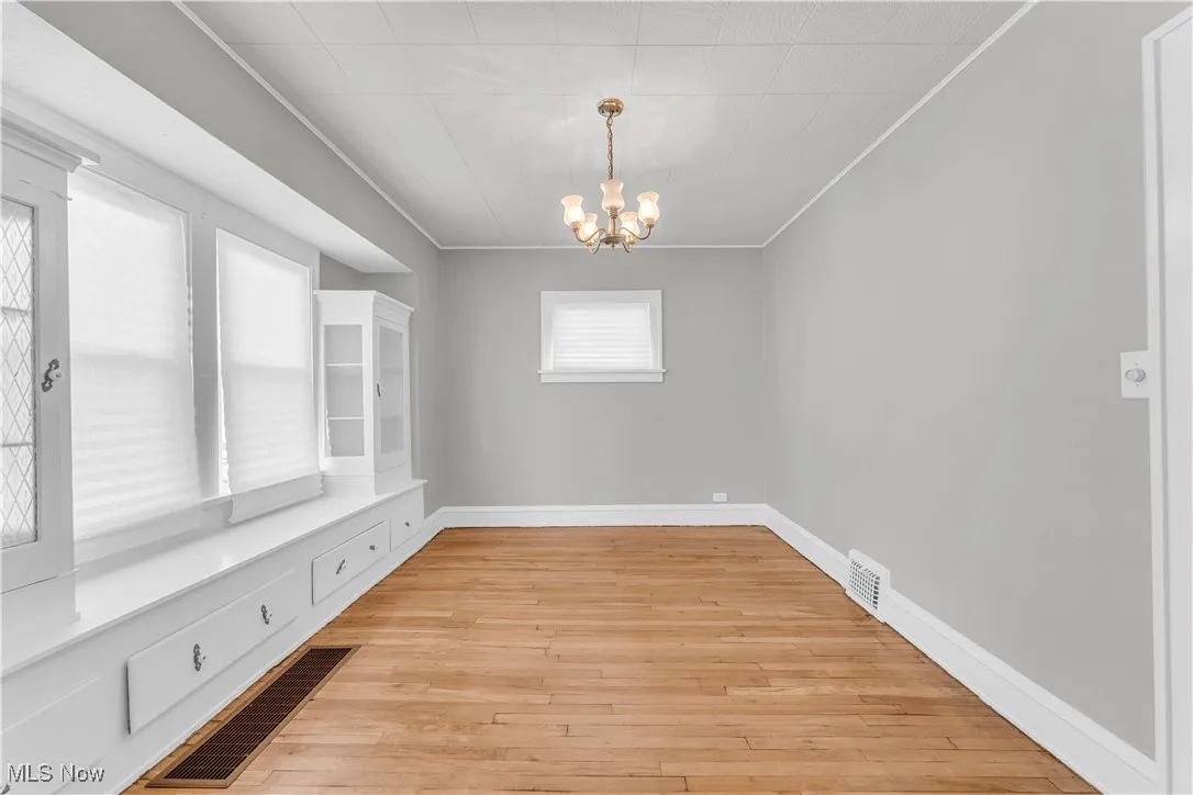 Unfurnished dining area featuring a chandelier, ornamental molding, and light wood-style floors