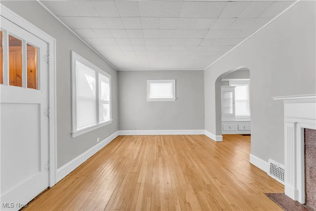 Unfurnished living room featuring arched walkways and light wood-type flooring