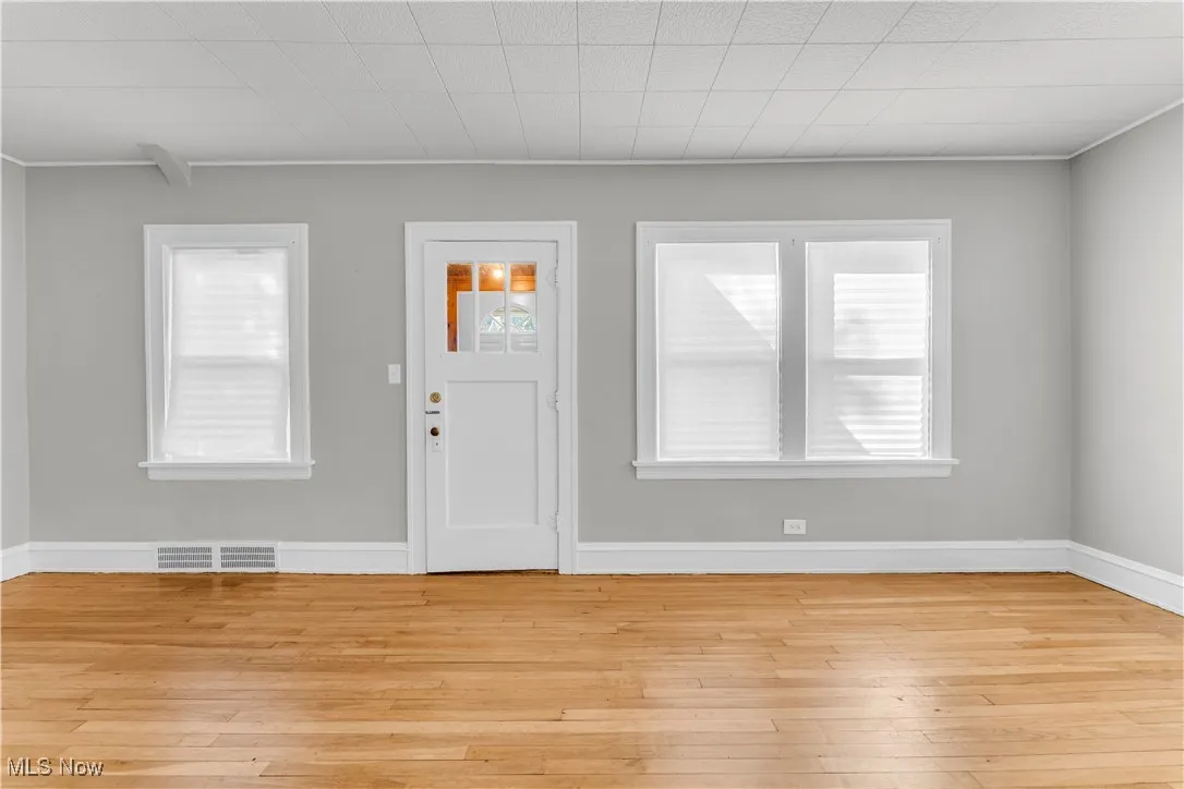 Foyer with light wood-style flooring and crown molding