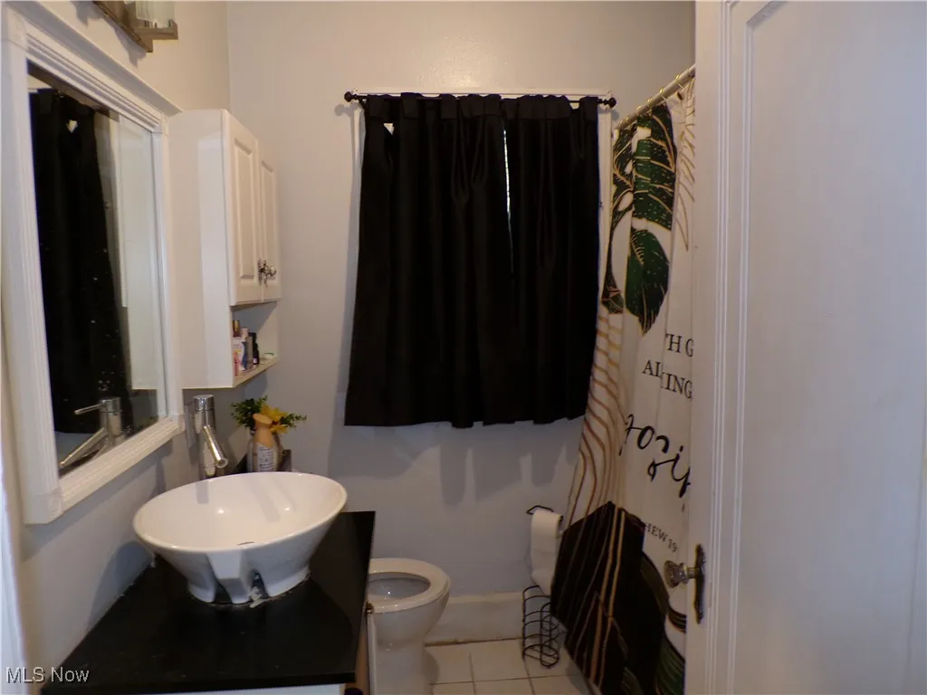Full bathroom featuring light tile patterned flooring and vanity