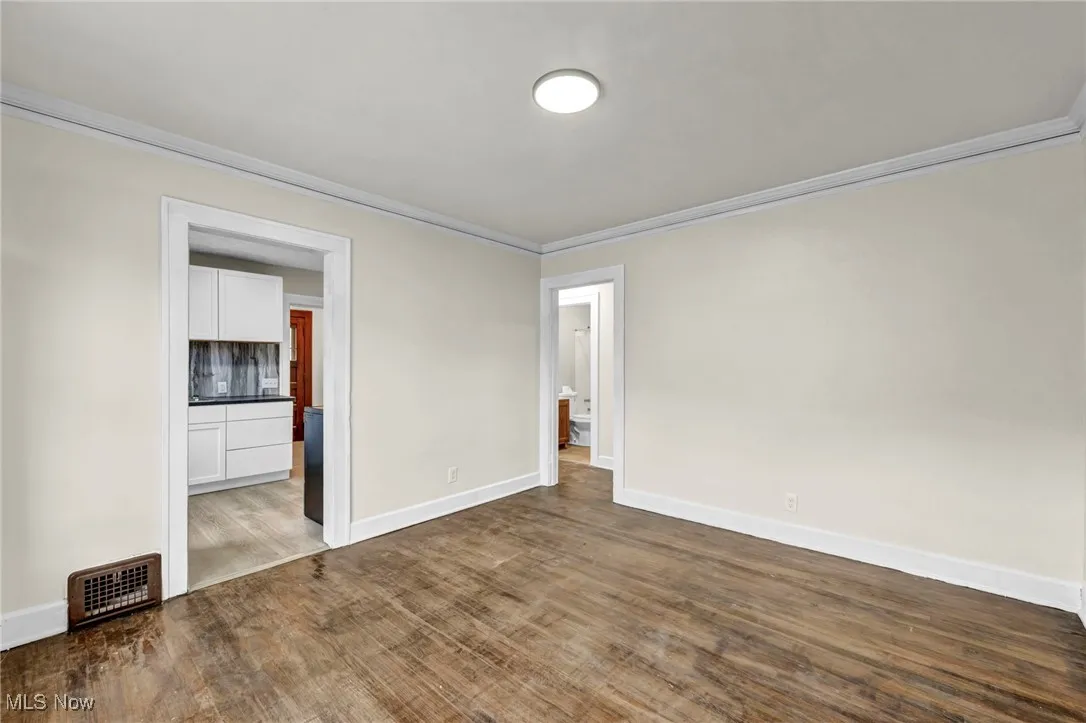Unfurnished bedroom with ornamental molding and dark wood finished floors