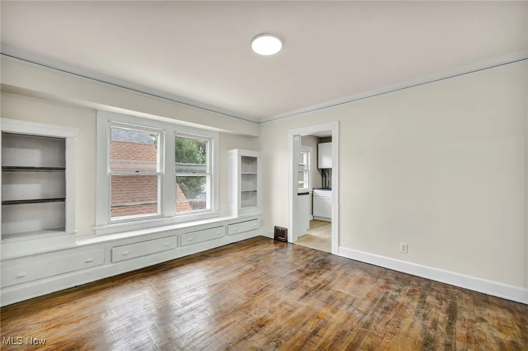 Spare room featuring wood finished floors and crown molding