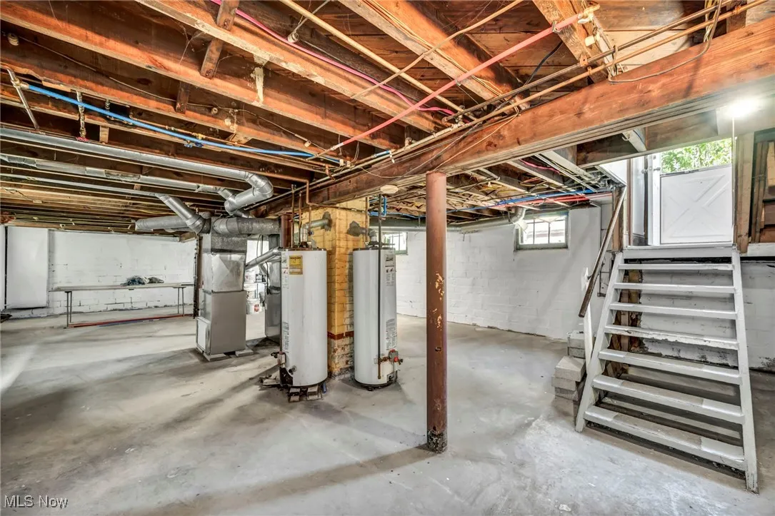 Basement featuring stairs, gas water heater, and heating unit
