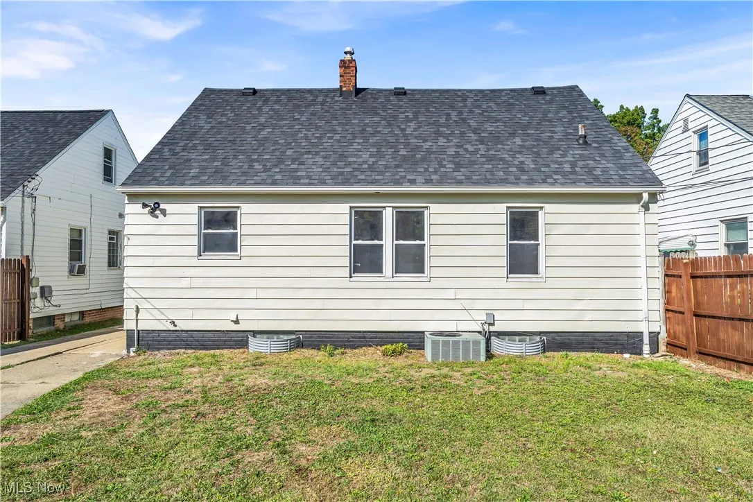 Rear view of house featuring a shingled roof and a chimney