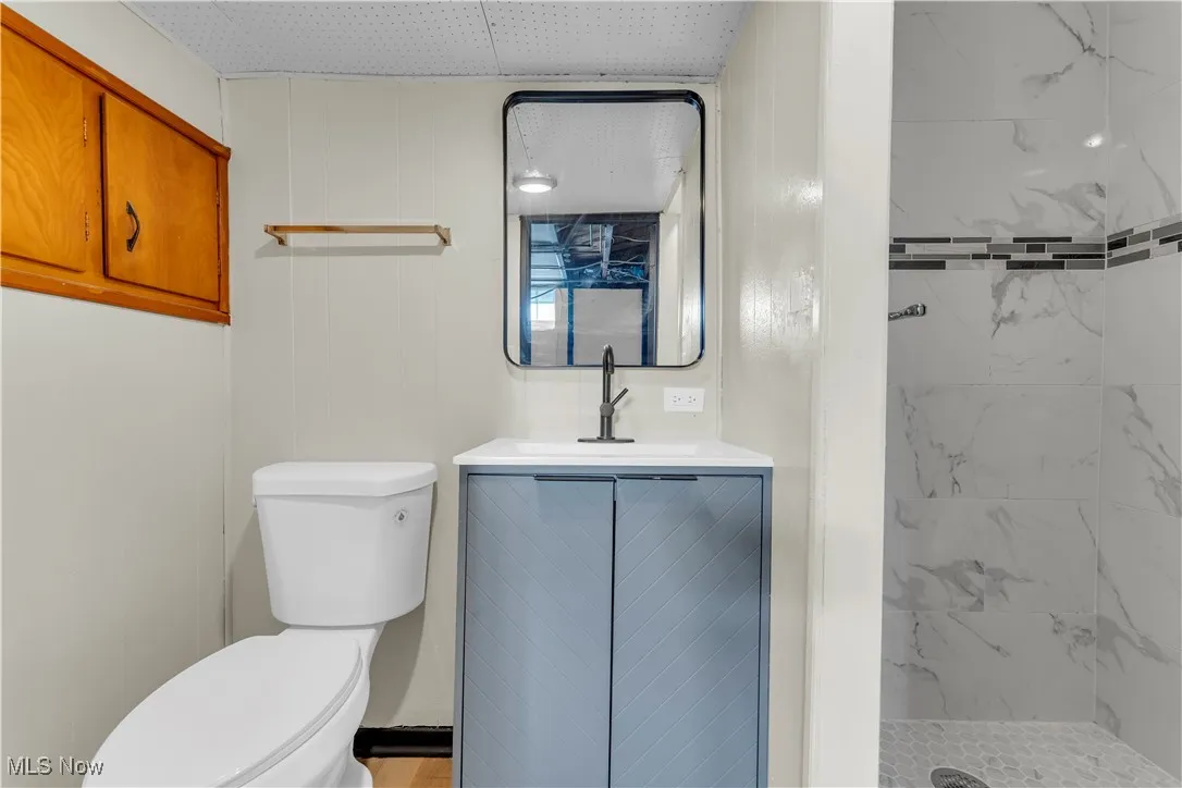 Bathroom with vanity and a marble finish shower
