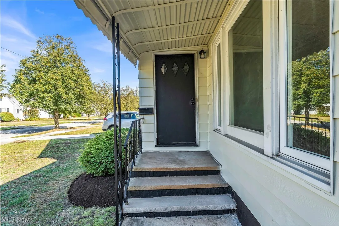 Doorway to property featuring a porch and a lawn
