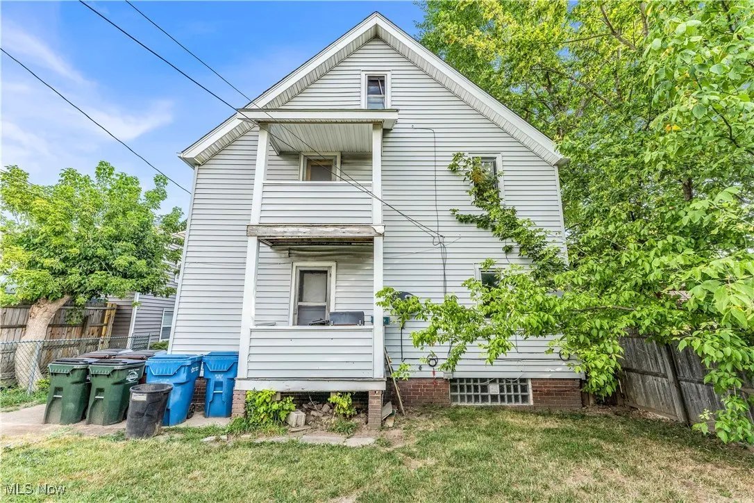 Back of house with a fenced backyard and a balcony