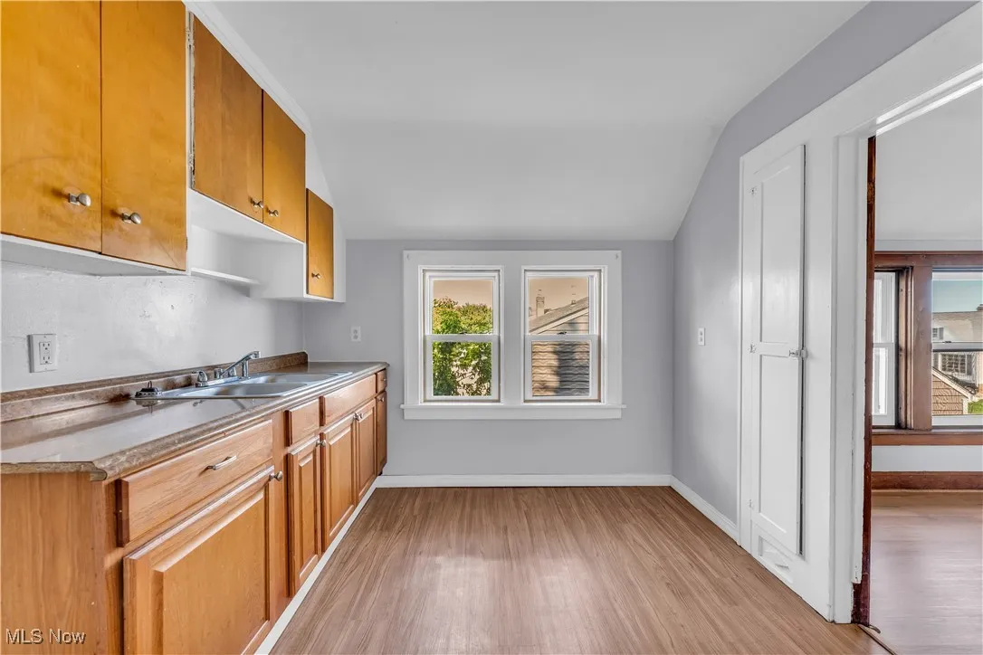 Kitchen with light wood-style flooring, brown cabinetry, and vaulted ceiling