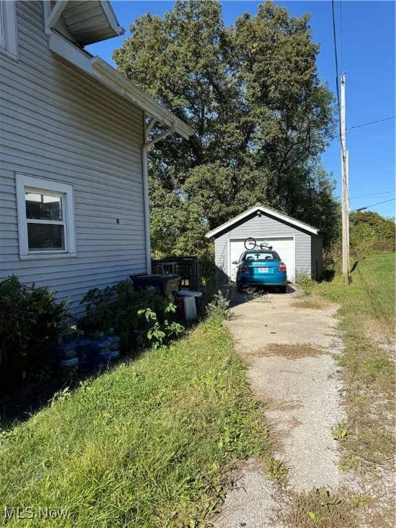 View of property exterior featuring a garage, an outdoor structure, and driveway
