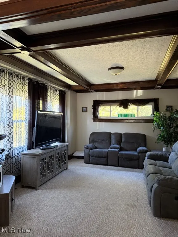 Carpeted living area with beamed ceiling and a textured ceiling