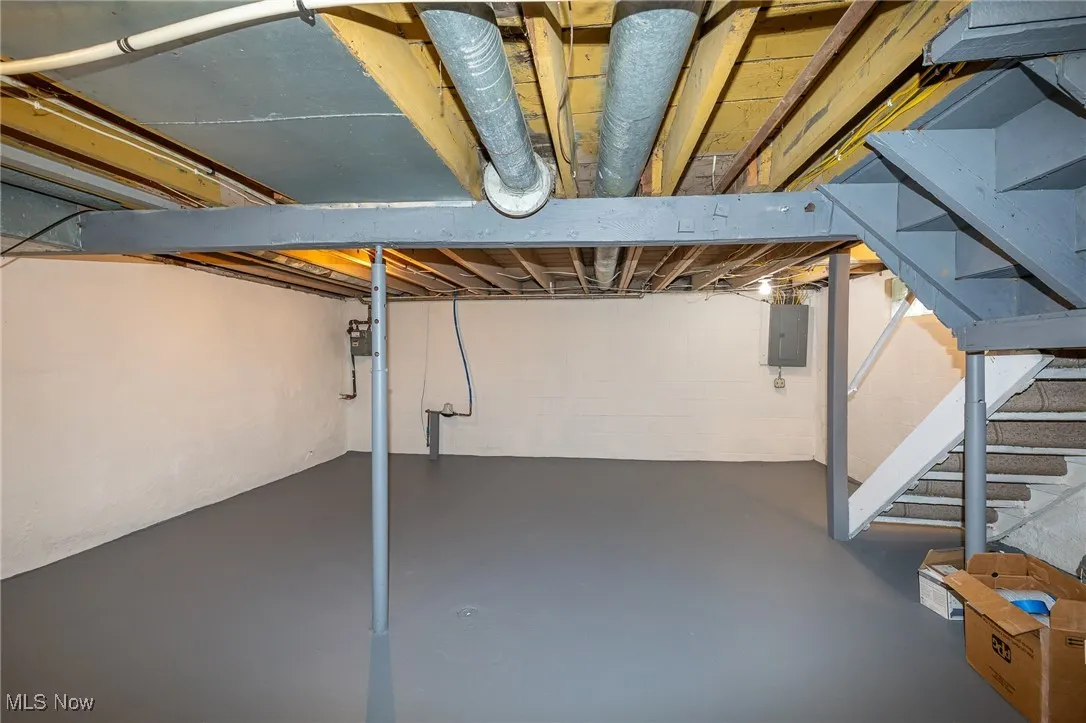 Unfinished below grade area with electric panel and stairway