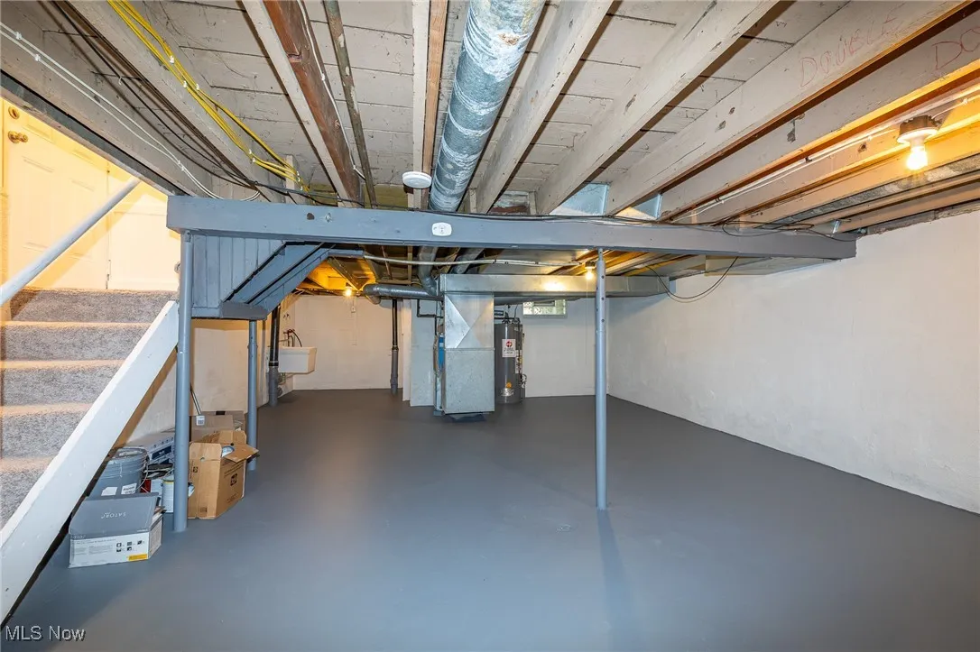 Unfinished basement featuring stairway, heating unit, and water heater. Freshly painted