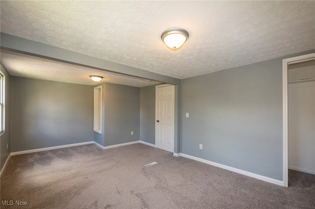 Unfurnished bedroom with a textured ceiling and light carpet