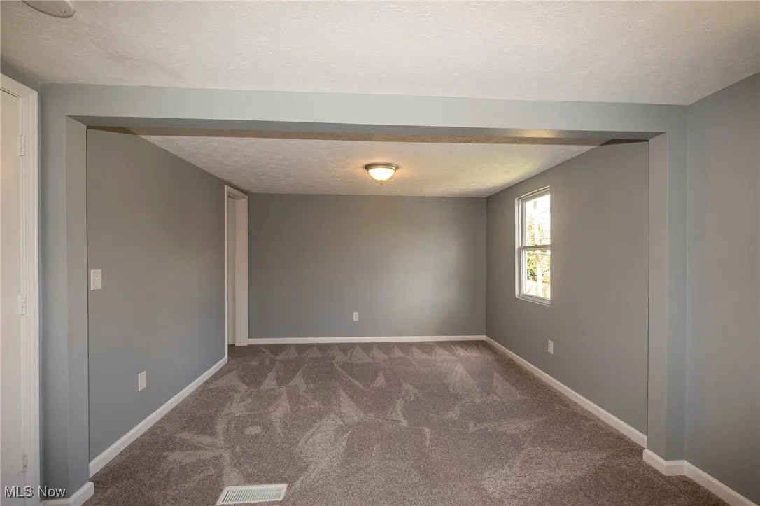 Newly Carpeted Bedroom featuring a textured ceiling and baseboards