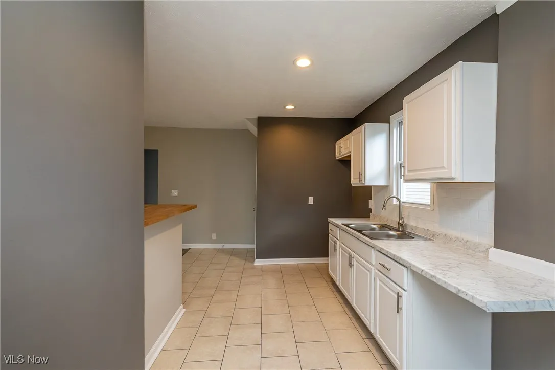 Kitchen with light countertops, recessed lighting, white cabinets, light tile patterned floors, and decorative backsplash