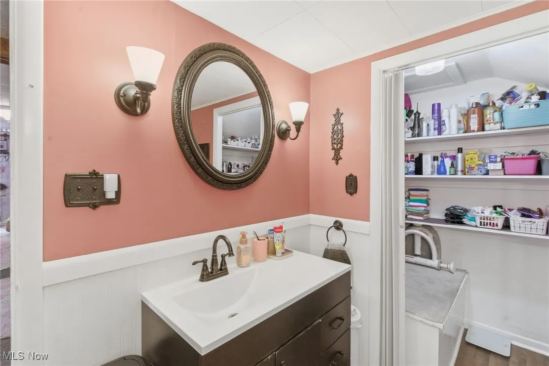 Bathroom featuring vanity, wainscoting, and crown molding
