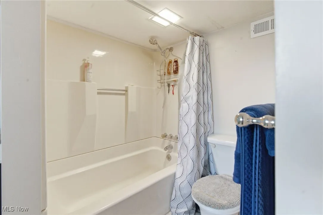 Full bath with shower / bathtub combination with curtain and toilet