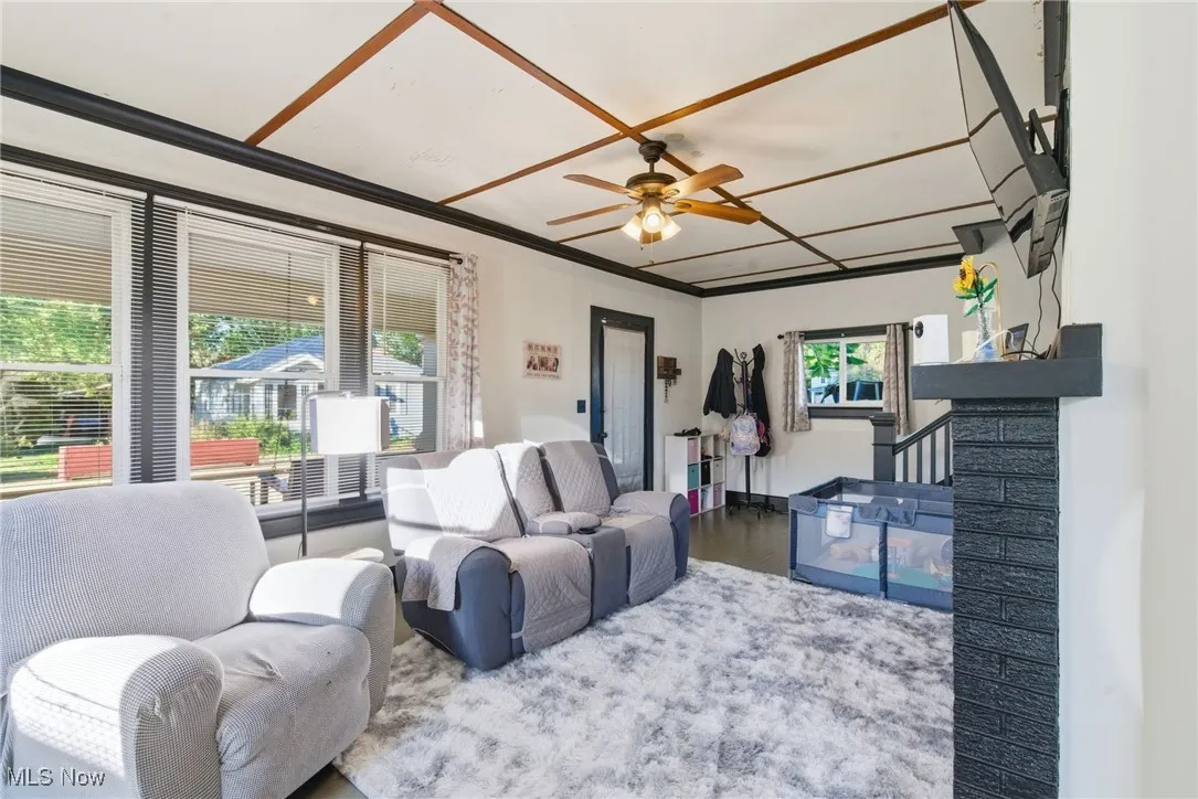 Living area featuring a ceiling fan, wood finished floors, and stairs