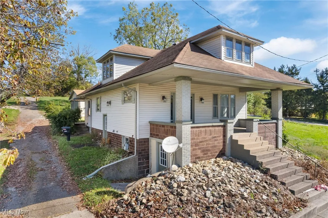 View of front of property featuring a porch, roof with shingles, and stairs
