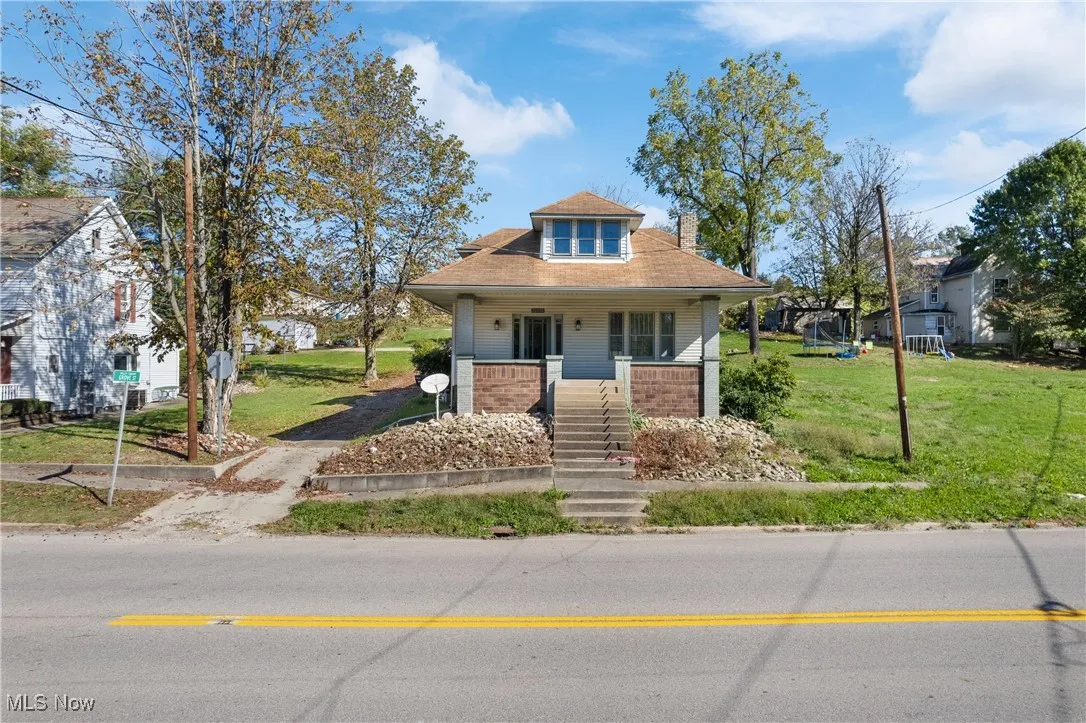 Bungalow featuring a front lawn, a porch, a chimney, and stairway