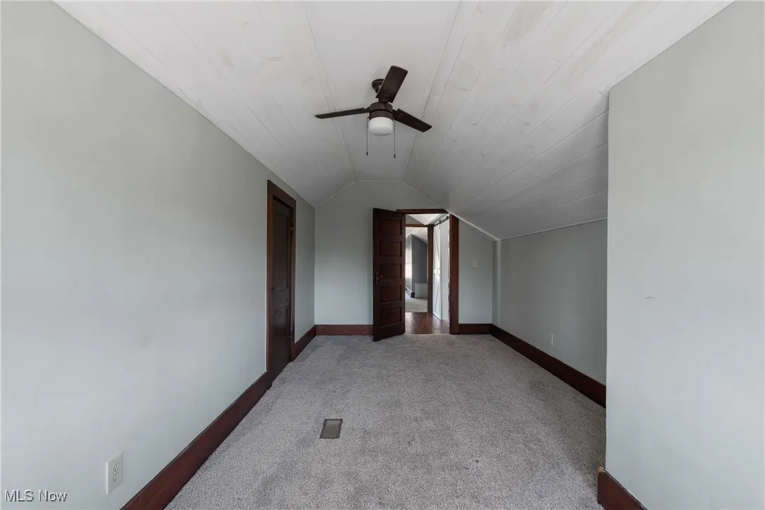 2nd floor bedroom featuring lofted ceiling, light carpet, and ceiling fan
