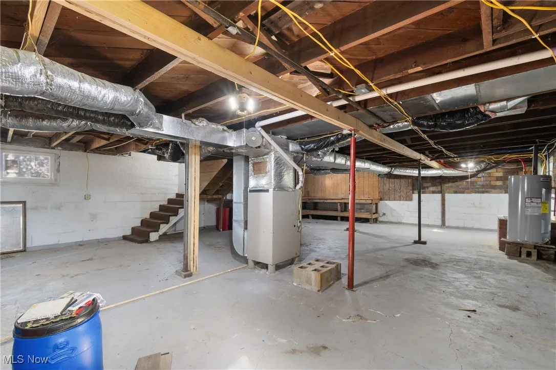 Below grade area featuring stairs, heating unit, and water heater