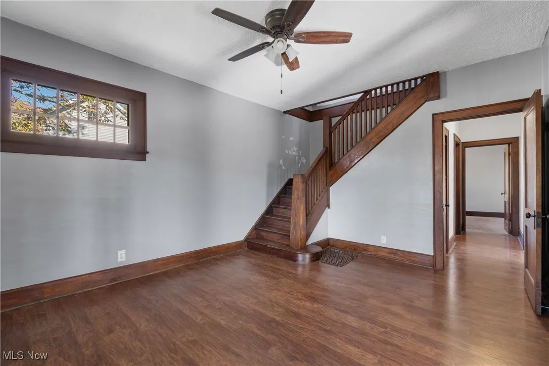 Foyer with dark wood-type flooring, ceiling fan, and staircase
