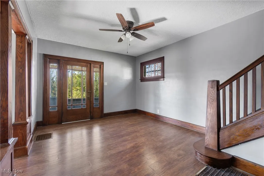 Foyer with a textured ceiling, dark wood finished floors, a ceiling fan, and stairs